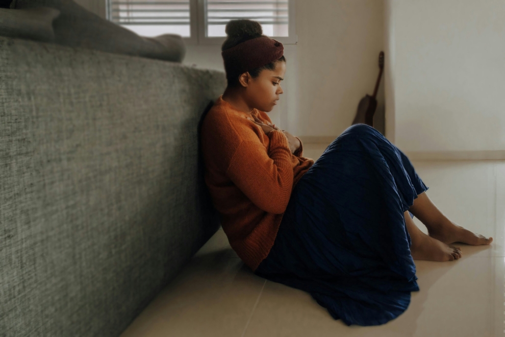 Woman sitting next to gray couch