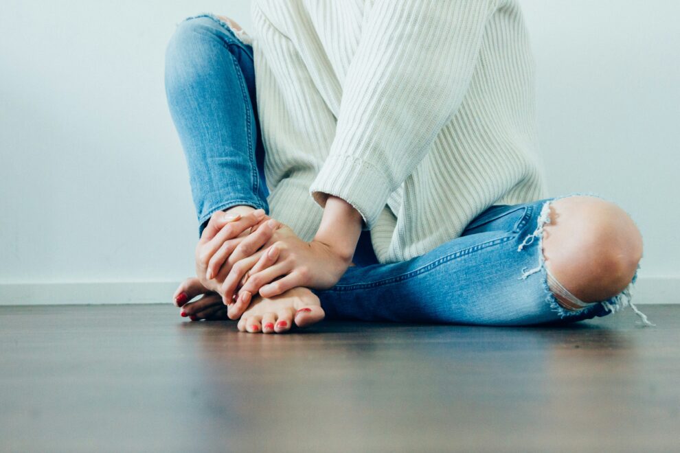 A barefoot person wearing blue jeans 