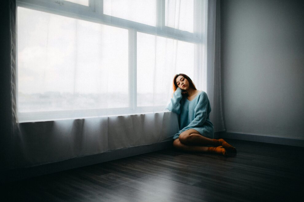 Woman sitting on floor near window